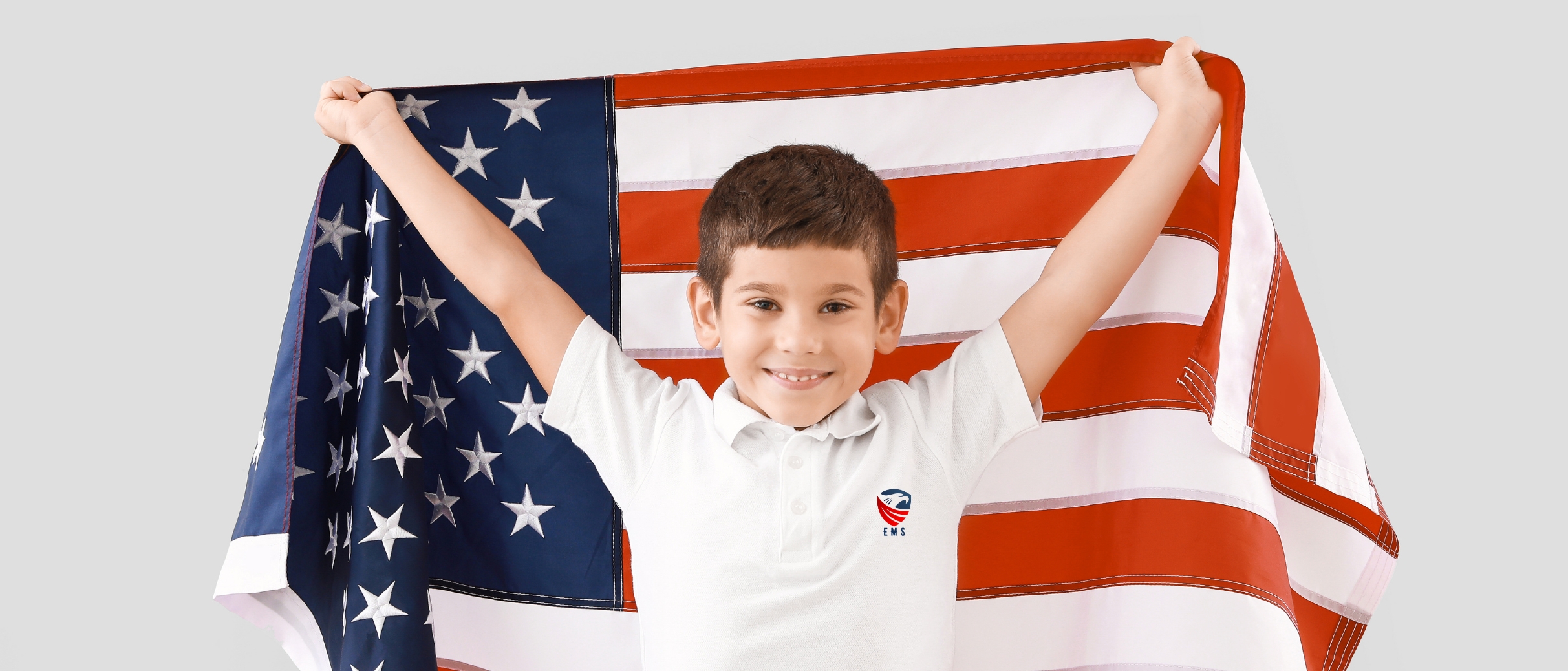 A boy smiles as he raises an American flag high in the air, as he got his usa visit visa approved.